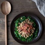 A photo of a bowl of black eyed peas with spinach and bacon