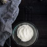 How to make Cake Flour or Bread Flour - a photo of flour in a bowl, surrounded by cornstarch, vital wheat gluten, a whisk and measuring spoons.