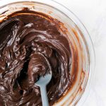 Homemade Chocolate Frosting in a bowl with a spoon.