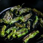 Blistered Shishito Peppers in a cast iron skillet