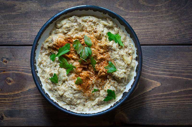 Baba Ghanouj in bowl, garnished with parsley and smoked paprika