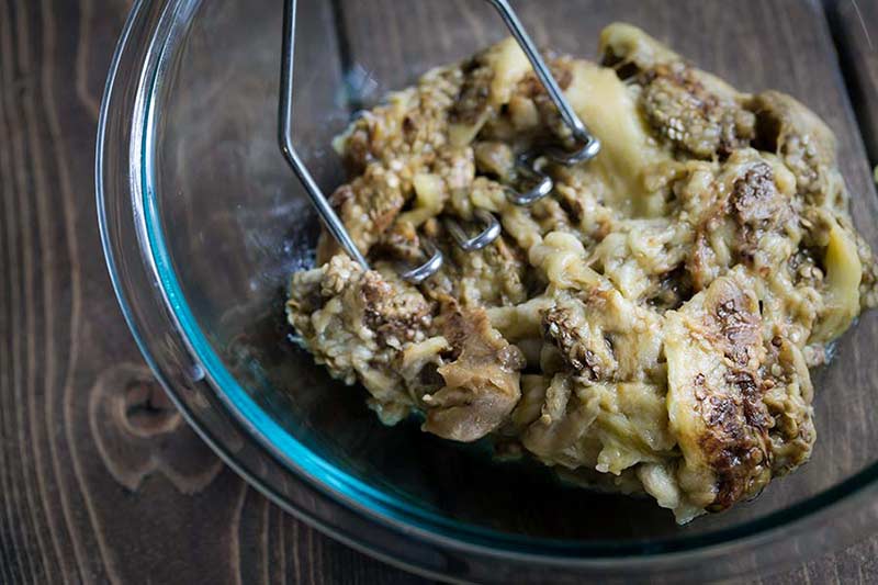 Mashing the eggplant in a bowl for baba ghanoush