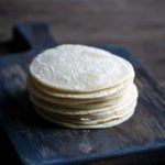 stack of homemade corn tortillas on a cutting board