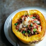 A Baked Spaghetti Squash Boat on a plate next to a fork