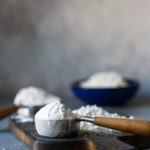 Different types of flour displayed in bowls and measuring cups