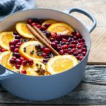 Stovetop potpourri ingredients in a Dutch oven, including orange slices and cinnamon sticks