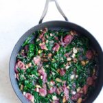 Sautéed spinach with grapes and almonds in a skillet shot from overhead